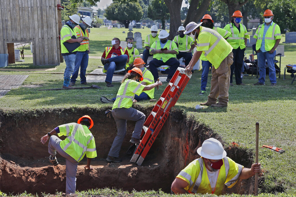 In this July 14, 2020, file photo, workers climb out of the excavation site as work continues on a potential unmarked mass grave from the 1921 Tulsa Race Massacre, at Oaklawn Cemetery in Tulsa, Okla. (AP Photo/Sue Ogrocki File)