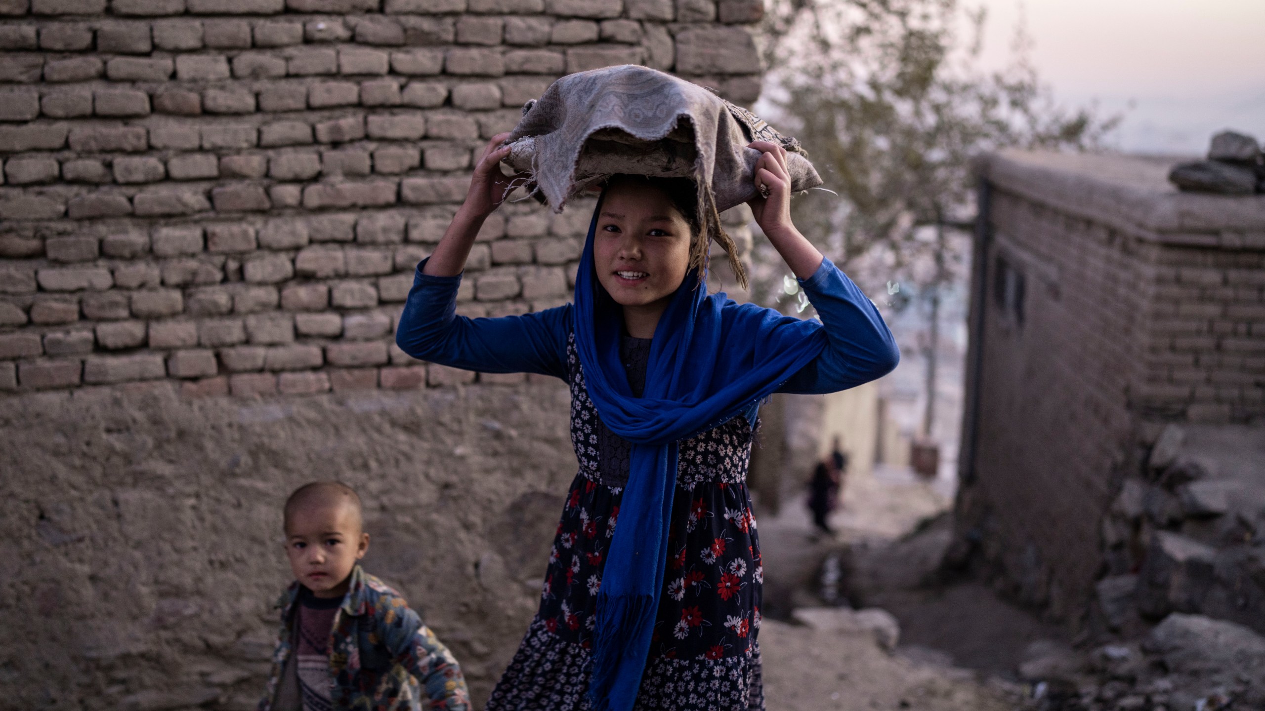 A girls carries bread as she leaves a bakery, in Kabul, Afghanistan, Sunday, Nov. 21, 2021. (AP Photo/Petros Giannakouris)